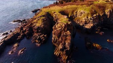 Steep cliffs over calm blue inlet. Steep weathered rock walls border a sheltered stretch of clear quiet sea.