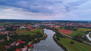 A town on the bank of a winding river under a twilight sky. A panorama of an evening town with brightly lit houses, situated next to a river at sunset.