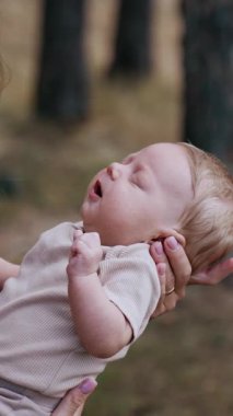 Loving mom puts her baby close to her chest. Caucasian woman with her child outdoors in autumn. Blurred backdrop. Vertical video