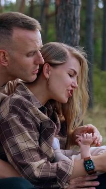 Caring parents calming down their crying baby. Mom and dad nursing their child spending time in nature. Vertical video