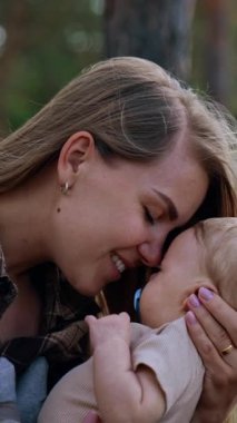 Loving mother leaning to her baby. Mom and son time spent in the nature. Side view. Vertical video