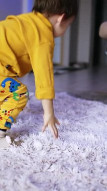 Cheerful energetic baby boy turning around. Adorable toddler having fun time at home. Vertical video