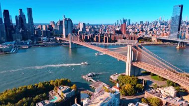 New York, ABD, 28 Ağustos 2025: ABD 'de Manhattan Köprüsü' nün altından iki tekne geçiyor. Açık mavi gökyüzüne karşı şehrin manzarası. Hava görünümü.