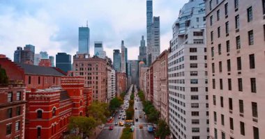 New York, ABD, 28 Ağustos 2025: Ağaçlarla çevrili uzun düz cadde. Yollardan geçen araba akışı. Çok katlı binaların cephelerinde uçmak. New York, ABD.