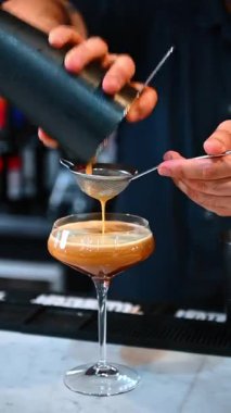 Barista kremalı kokteyl süzüyor. Kyiv, Ukrayna, 23 Ağustos 2025: Sarsılan kremalı bir içecek, barda bir coupe bardağına bağlanıyor..