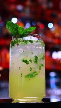 Parlak naneli kokteyl yakın plan. Nane ve buz karışımı, bar aydınlatması altında yakalanan canlandırıcı canlı bir kokteyl..