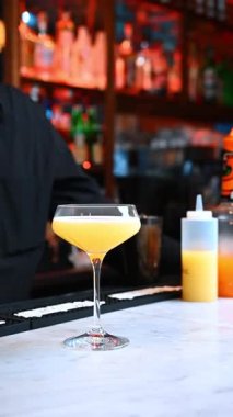 Limonlu kokteyl. Kyiv, Ukrayna, 23 Ağustos 2025: Parlak bir limon dilimi barda pürüzsüz sarı bir kokteyli süslüyor.