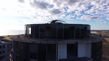 Silindir şeklindeki binanın yuvarlak çatısı. İnşaatın İHA görüntüleri bulutlu gökyüzüne karşı oturur.