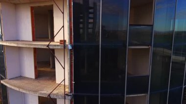 Yüksek binalar yapım aşamasında. Perde boyunca boş kapılar ve bitmemiş balkonlarla ilerliyoruz..