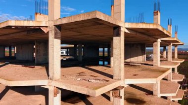 İnşaat halindeki çok katlı binanın çimento gövdesinden uzakta. Arkaplanda sera ve konutlar.