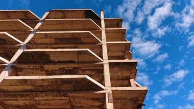 Geleceğin binasının tepesine çıkıyoruz. İnşa edilmiş evin perdesinin alçak açılı görüntüsü. Arkaplanda kabarık bulutlu mavi gökyüzü.