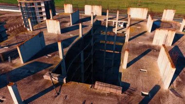 Çok katlı bina inşaatının iskeletinin üzerinden uçuyor. Arkaplanda hareket halindeki arabalarla otoyol.