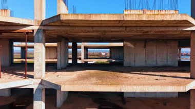 İnşaat halindeki binanın içinden uçuyor. Arkaplanda deniz kıyısındaki resimli yerleşim yeri.