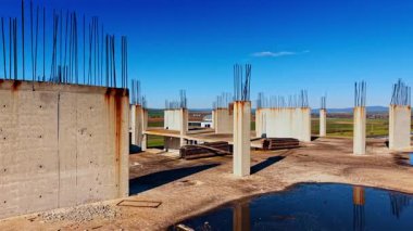 Terk edilmiş çok katlı binanın tepesinde su birikintileri var. Arkaplanda yeşil kırsal ve dağ sıraları.