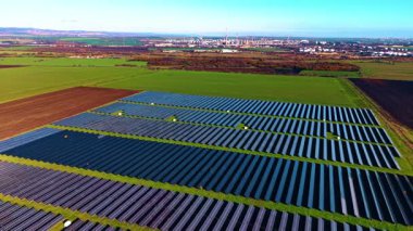 İnsansız hava aracının geniş alanlardaki güneş panelleri üzerindeki görüntüleri. Arkaplanda petrol rafineri tesisi.