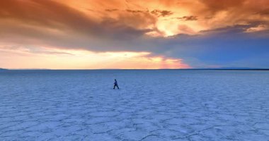 Uçsuz bucaksız tuzlu arazide yürüyen bornozlu adama yaklaşıyoruz. Günbatımında Utah Bonneville Salt Flat 'i ziyaret ediyorum..