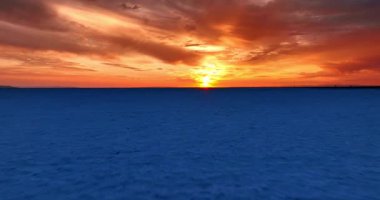 Bonneville Salt Flat, Utah, ABD 'deki tuzlu araziden hızlı bir uçuş. Gökyüzü ve bulutlar gün batımında turuncu ışıkta.