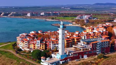 Yanı başındaki deniz feneri olan konut binalarının canlı manzarası. Bulgaristan 'ın Aheloy kentindeki Marina Cape kompleksi civarındaki İHA görüntüleri.