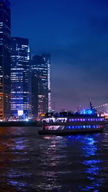 Dark silhouettes of people are on the upper deck of the cruise boat. Night river tour around New York. Vertical video.