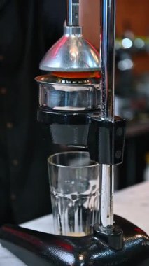 Mavi üniformalı, eldivenli, portakal suyu sıkan tanınmamış biri. Barmen taze meyve suyuyla bir içki hazırlar. Dikey video.