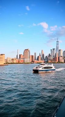 Sürat teknesi gündüz vakti East River 'a yaklaşıyor. Arka planda New York 'un silüeti. Dikey video.