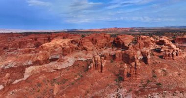 ABD 'deki Arches Ulusal Parkı' ndaki sütunlu kayalara yakın uçuyor. Bulutlu gökyüzünün altındaki engin kayalık çöl.