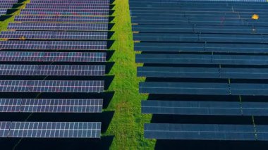 Yeşil alanlarda bir sürü güneş paneli var. Güneş, birden fazla fotovoltaik hücreyle kaplı geniş bölgeyi aydınlatıyor. Hava görünümü.