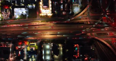 Aydınlatılmış yol kavşağı, birden fazla araba geçiyor. Geceleri otoban ve trabzanların yanından geçen araba akışı. Hava görünümü.