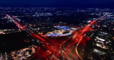 Çarpıcı bir yol sistemiyle engin, aydınlık şehir manzarası. Geceleri kırmızı sokak lambalarıyla dolu bir kavşak. Hava görünümü.