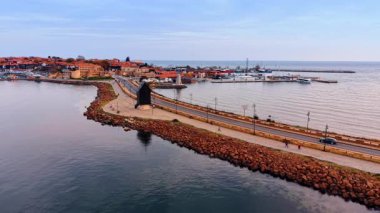 İnsanlar deniz manzarası boyunca barajın üzerinde karayolu boyunca yol boyunca yürüyorlar. Bulgaristan 'ın Nessebar kentinin manzarası İHA' dan.
