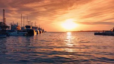 Göz kamaştırıcı batan güneş, Karadeniz 'in su manzarasını renklendiriyor. Rıhtımda bir sürü balıkçı teknesi var. Nessebar, Bulgaristan.