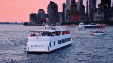 New York, ABD, 1 Ağustos 2025: Çeşitli tekneler doğu nehri su yatağının çapasında duruyor. Pembe gökyüzüne karşı güzel şehir silüeti.