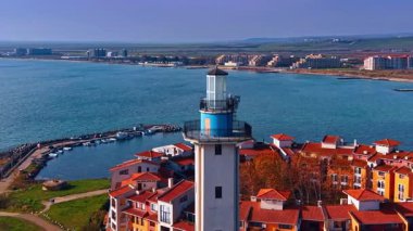 Aheloy deniz feneri kuleleri Marina Cape kompleksindeki kırmızı çatılı evlerin üzerinde. Bulgaristan 'daki tekneler ve geniş Karadeniz suları için döşeli barajın havadan perspektifi.