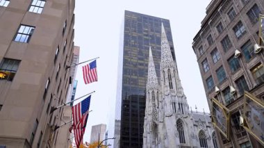 New York, ABD, 22 Ekim 2025: Saks Fifth Avenue cephesi ve St. Patrick Katedrali. Amerikan bayrakları karşı binanın perdesine asılmış. New York, ABD.