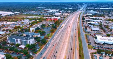 Geniş şehir manzarasından geçen çok şeritli otoyollar. Sayısız araba hızla yoldan geçer. Hava görünümü.
