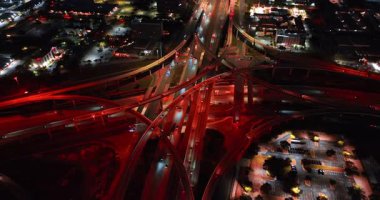 Karmaşık yol kavşağından uzaklık sokak ışıklarıyla kırmızıya boyanmış. Birçok araba gece kavşağın yanından geçiyor..