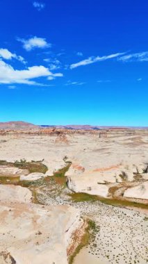 Muhteşem kanyonları olan terk edilmiş kayalık bir arazi. Yukarıdaki mavi gökyüzünde küçük kabarık bulutlar. Powell Gölü 'ndeki Lone Rock Plajı Kampı. Dikey video.