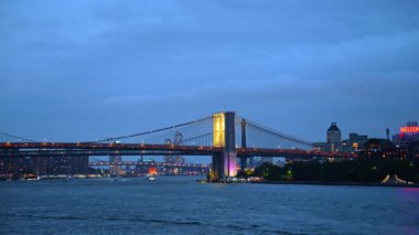 New York, ABD, 2 Ekim 2025: Brooklyn Köprüsü geceleri aydınlık. Gün batımında nehir manzarasından New York 'un simgesine bakın..