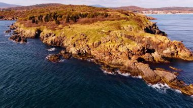 Rugged rocky shore with vegetation at backdrop. Drone footage over the waterscape at the coast.