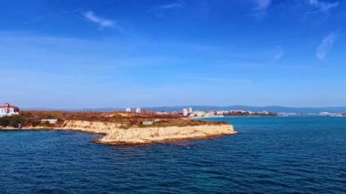 Açık Mavi Deniz ve Güneşli Gökyüzü Manzaralı Sahil Adası. Parlak mavi gökyüzünün altında turkuaz deniz sularıyla çevrili Rocky sahil adası..