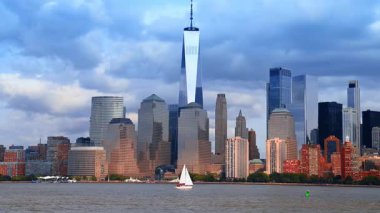 Beyaz yelkenli, Doğu Nehri 'nin sularından geçiyor. Arkaplanda bulutlu gökyüzüne karşı New York silüeti.