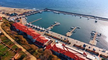 Karadeniz kıyısında kırmızı çatılı evler, geniş rıhtım ve yatlar için rıhtımlar. İHA görüntüleri Bulgaristan kıyıları üzerinde.