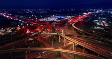 Göz kamaştırıcı bir aydınlatma ile güzel bir şehir manzarası. Hızlı hareket eden arabalarla canlı bir kavşağın etrafında İHA uçuşları.