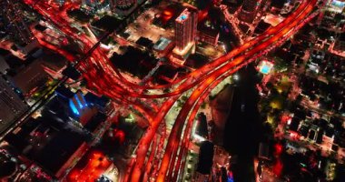 Canlı, çok katlı bir kavşak gece kırmızıda parlıyordu. Miami, Florida, ABD 'deki otoyollarda yüzlerce araba çalışıyor. Üst görünüm.
