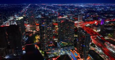 Nehrin üzerindeki yüksek binalara yaklaşıyoruz. Geceleri Miami, Florida 'nın göz kamaştırıcı manzarası.