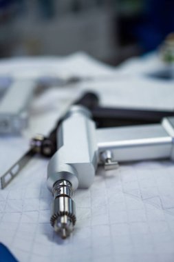 Diğer ekipmanlarla çevrili beyaz bir yüzeye bir araç yerleştirilir. Bir teknisyen yoğun bir atölyede bir proje üzerinde çalışmaya hazırlanırken görülebilir..