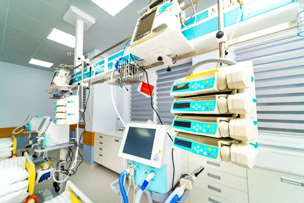 Tıbbi malzemeler hastane odasının duvarlarını kaplıyor. Hasta bakımı için monitörler ve makineler kuruldu. Oda temiz ve tıbbi işlemler için düzenlenmiş..