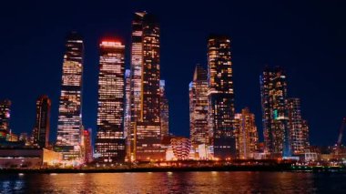 New York, ABD, 9 Aralık 2025: ABD 'nin New York şehrinin aydınlık gökdelenleri arasında Vessel Yapısı. Nehir manzarasının çarpıcı mimarisine alçak açı görünümü.