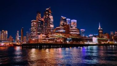 Yakınlarda çıplak ağaçlar ve tekneler olan uzun bir iskele. Tekne geceleri New York 'ta geziyor..