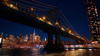 Manhattan Köprüsü 'nün altından tekneyle geçeceğiz. Sokak aydınlatması açık olacak. Arka planda New York 'un nefes kesen parlak silueti.